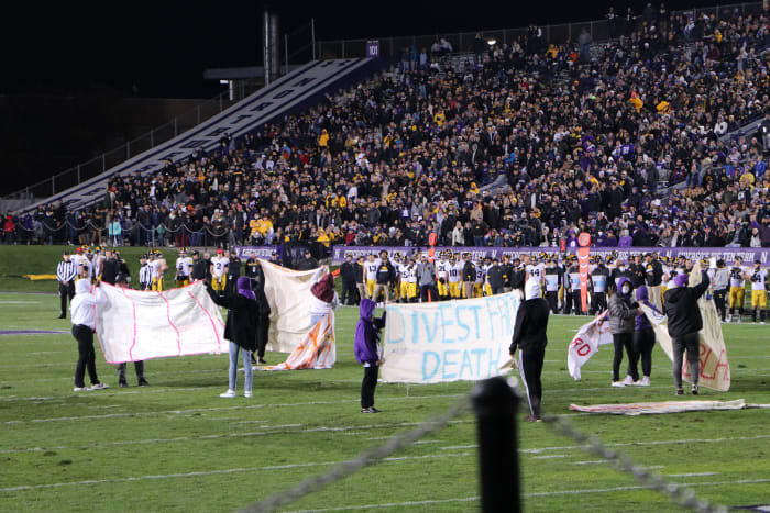 Nine protesters took the field to display handmade signs during the first half of Northwestern vs. Iowa on Saturday, Nov. 6, 2021. (Photo by Lauren Withrow)